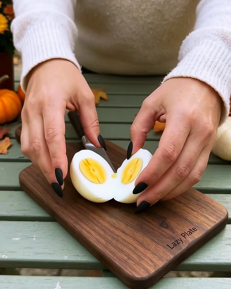 A peeled egg cut in half on a walnut board