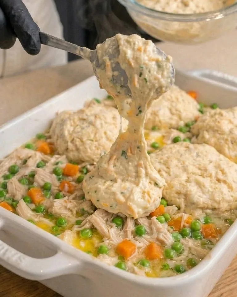 Dropping mounds of cheddar biscuit batter over the chicken
