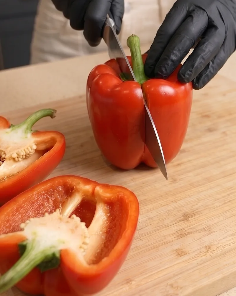 Cutting a red bell pepper in half through the stem