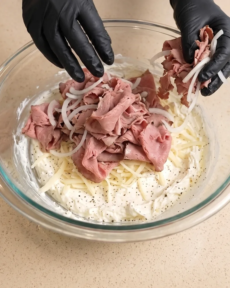 Chopped roast beef and onion over cream cheese in a glass bowl