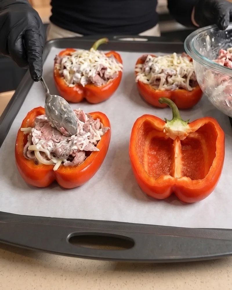 Spooning the beef filling into pepper halves on a sheet pan